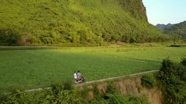 Vue supérieure les gens Ride scooter le long du champ contre la montagne — Video