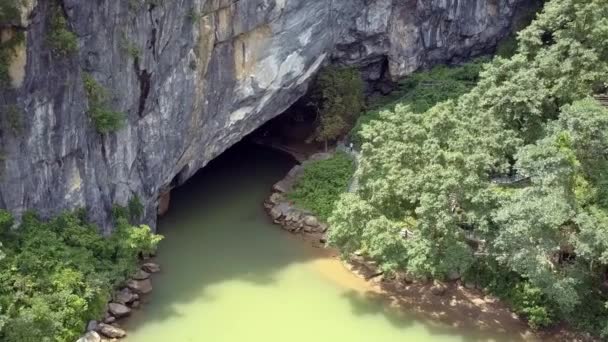 Aerial motion to cave gate and calm river in national park — Stock Video