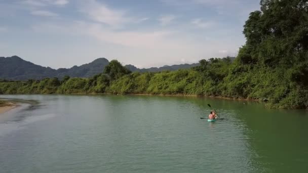 Parte posteriore superiore coppia in canoa vele alla riva del fiume forestale — Video Stock