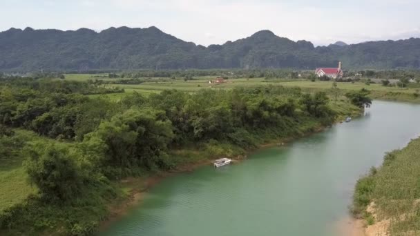 Vista aérea barco blanco cerca de la orilla verde del río contra colinas — Vídeo de stock