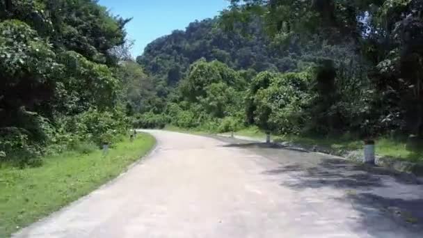 Kręta droga z szarymi i białymi paskami przed zielonymi wzgórzami — Wideo stockowe