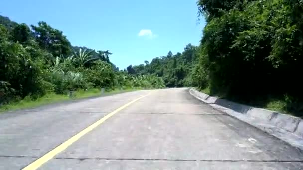 Grijze weg langs zwarte en witte palen tegen groene heuvels — Stockvideo