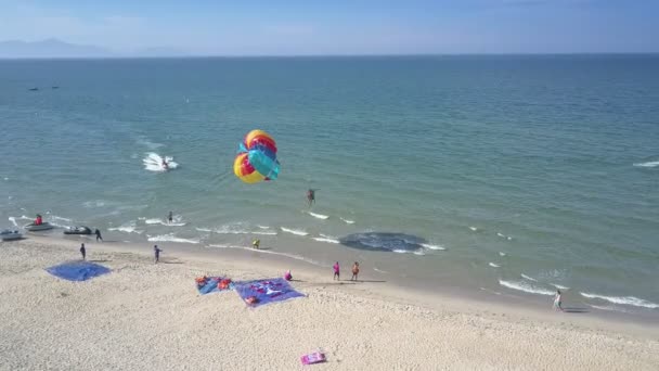 Pessoa vista aérea com pára-quedas voa sobre o oceano azul-turquesa — Vídeo de Stock