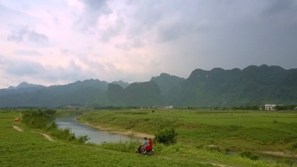 Uomo e donna cavalcare moto lungo il fiume tranquillo e campo — Video Stock