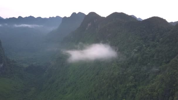 Pequenas nuvens cinzentas presas entre altos picos de montanha íngremes — Vídeo de Stock