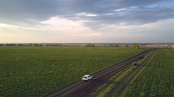 voiture éclairée par le coucher du soleil conduit le long de la route étroite sale 