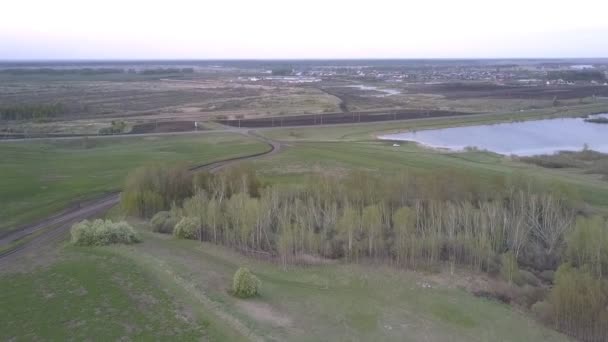 Lago azul entre los campos cerca de la carretera ancha contra pueblo — Vídeos de Stock