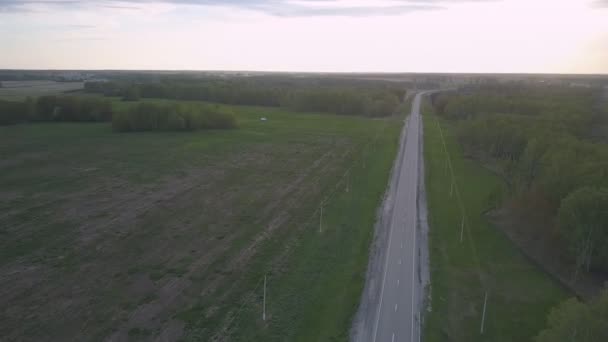 Biały samochód jedzie z drogi gruntowej do autostrady o zmierzchu — Wideo stockowe