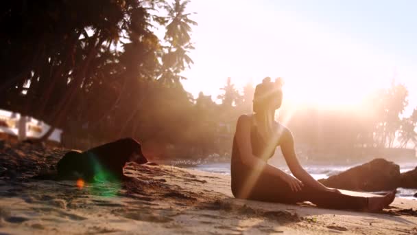 Silhouettes pieds nus dame et chien éclairées par le soleil du matin — Video