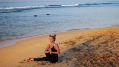 siyah eşofmanlı bayan dalgalara karşı meditasyon oturur