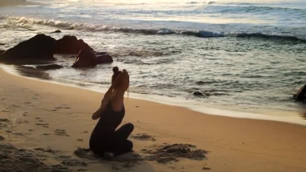 Young beautiful woman stretches doing yoga against ocean — Stock Video