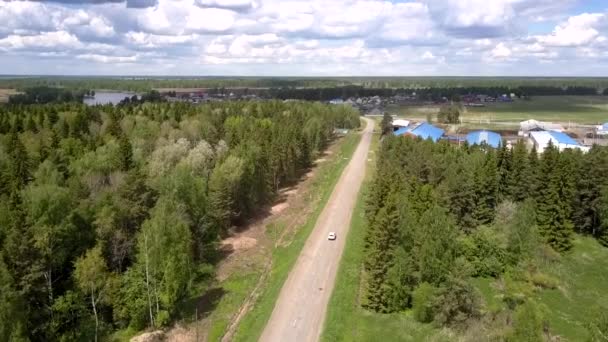 Cruce de unidades a la aldea a lo largo de camino gris cerca de los bosques — Vídeo de stock