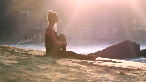 Silueta dívky osvětlená jitřním sluncem sedí v jókové poloze — Stock video