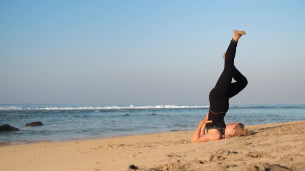 Jeune belle femme en survêtement noir pratique le yoga — Video