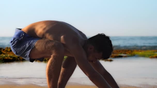 Захватывающий спотчер в синих шортах делает упражнения на пляже — стоковое видео