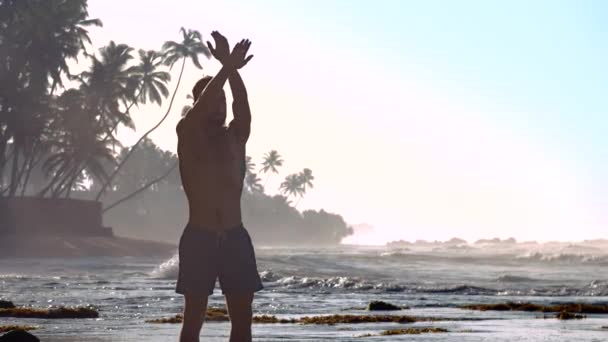 Hombre musculoso silueta medita en la costa del océano por la mañana — Vídeo de stock