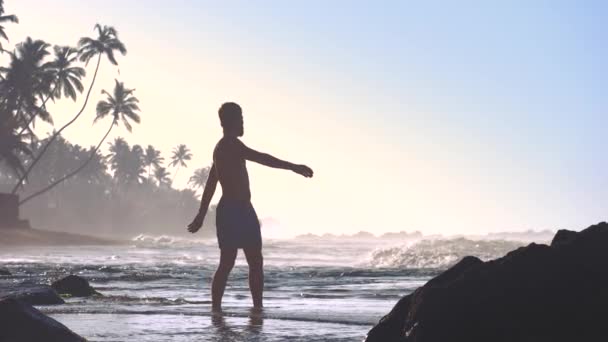 強い男のシルエットは、海の海岸に戻って伸び回す — ストック動画