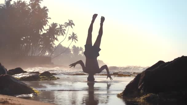 Fuertes equilibrios de silueta de gimnasta en la cabeza sobre arena mojada — Vídeo de stock