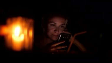 kız siyah telefon ile oturur ve mum ile internet sörf