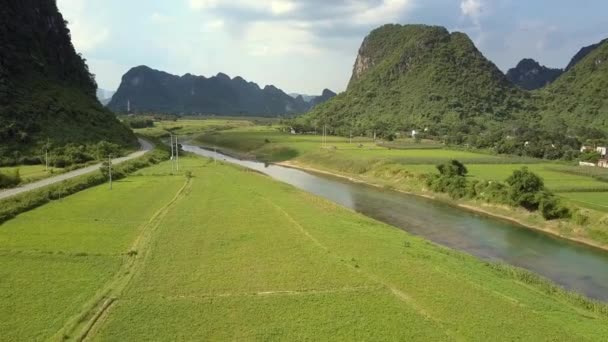 Vallei met velden weg en smalle rivier bij de bergen antenne — Stockvideo