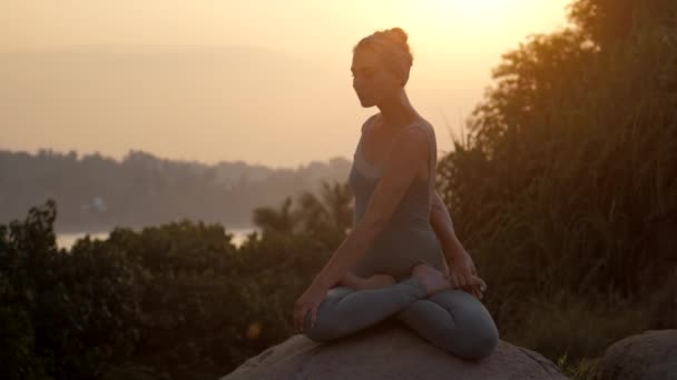 Praktizierende sitzt in drehbarer Lotus-Pose auf Felsen-Zeitlupe — Stockvideo