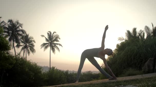 Esnek kadın yolda yavaş hareket trikonasana duruyor — Stok video