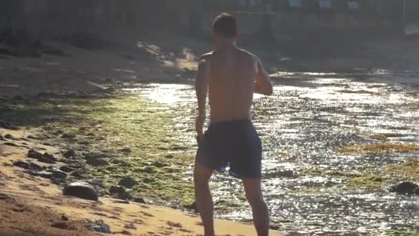 Sterke man loopt langs geel zand en bruine rotsen traag — Stockvideo