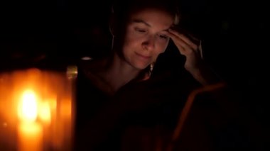 bayan siyah akıllı telefon tutan mum arkasında gece oturur