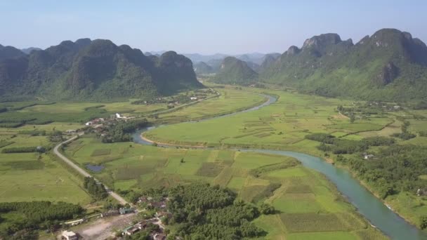 Tierras de cultivo con carretera y río entre montañas vista aérea — Vídeo de stock