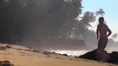 jimnastikçi kahverengi kayalar ile sarı kumlu plaj boyunca çalışır