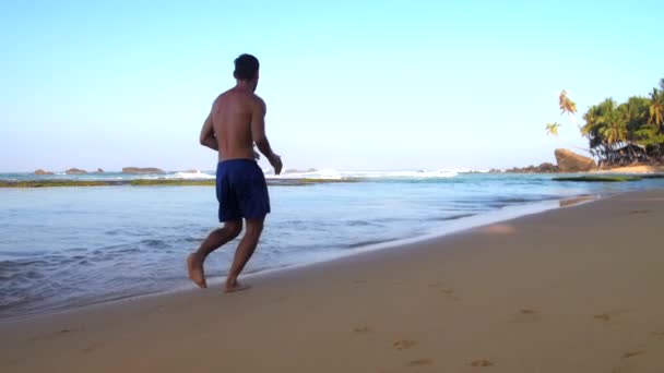 Atleta descalço corre ao longo da areia molhada no oceano lento — Vídeo de Stock