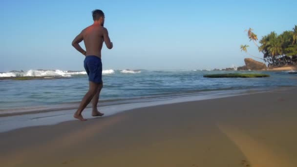Atleta profesional corre a lo largo de la playa de arena en verano — Vídeo de stock