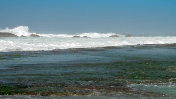 Forti onde oceaniche si schiantano contro rocce marroni con schiuma bianca — Video Stock