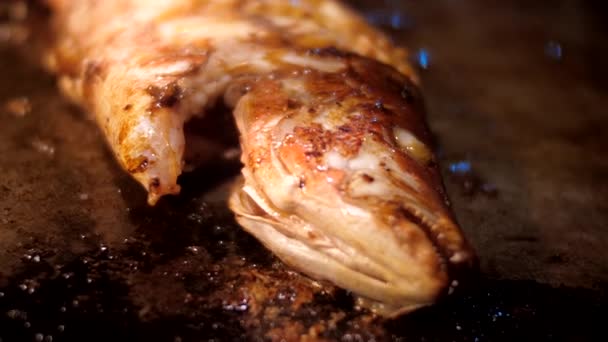 Традиційно варена риба лежить у темній сковороді з олією — стокове відео