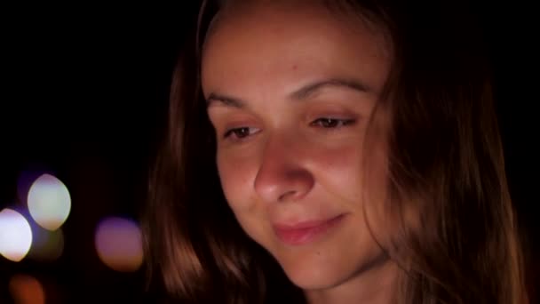 European girl sits in night background with bright spots — Stock Video