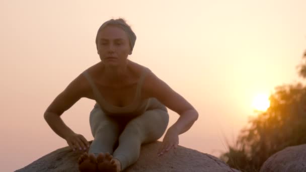 Mince dame fait yoga formation sur la pierre au lever du soleil au ralenti — Video