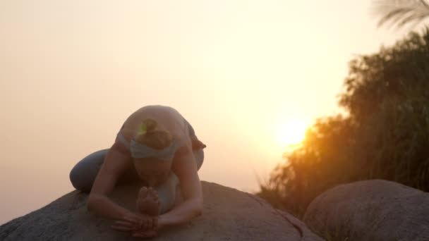 女性は大きな岩のスローモーションでヤヌシルサタナアダナでリラックス — ストック動画