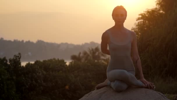 Frau in Grau steht in Gomukhasana auf altem Stein in Zeitlupe — Stockvideo