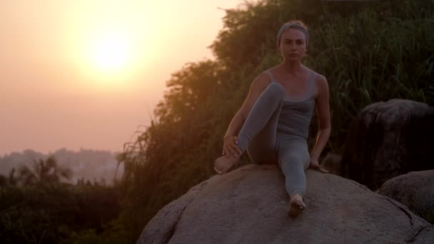 Женщина практикует йогу на сером камне замедленной съемки — стоковое видео