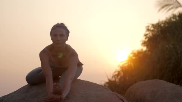 Vrouw zit in janusirsasana asana op Old Rock Slow Motion — Stockvideo