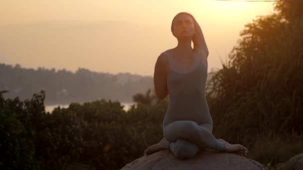 Practicante de yoga se sienta en gomukhasana sobre roca cámara lenta — Vídeos de Stock