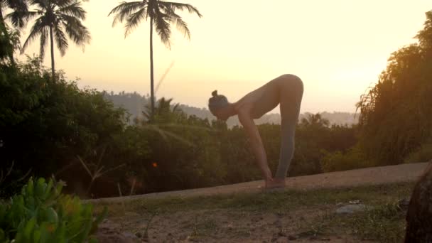 Señora delgada hace sol saludo yoga pose en pista cámara lenta — Vídeo de stock