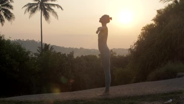 Ragazza alza le mani facendo yoga all'alba rallentatore — Video Stock