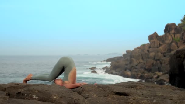 Изменения практикующего йоги позируют на плоском камне замедленной съемки — стоковое видео