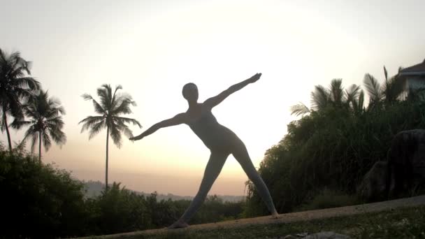 Praticante mostra trikonasana em estrada vazia câmera lenta — Vídeo de Stock