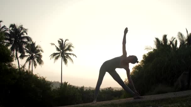 Практикующий йоги выходит из позы треугольника замедленной съемки — стоковое видео