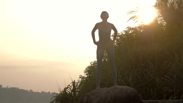 Vrouw buigt over het doen van Uttanasana op Rock Slow Motion — Stockvideo