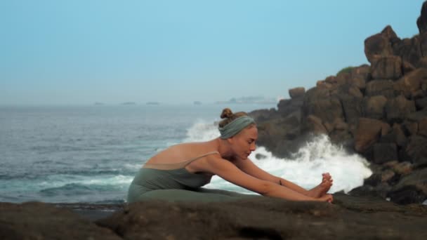 Vrouw doet Paschimottanasana op zee kust Slow Motion — Stockvideo