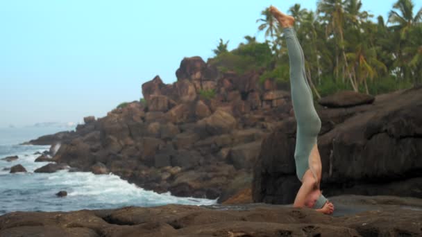 Dama de gris hace yóguico headstand en plana roca cámara lenta — Vídeos de Stock