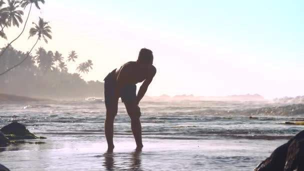 Gimnastyk stoi w płytkiej wodzie z rękami na kolanach — Wideo stockowe